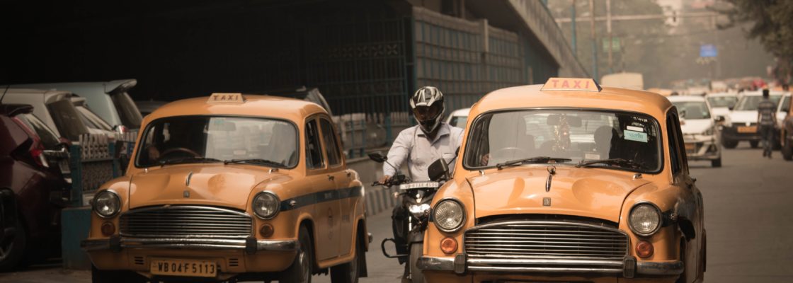 Yellow taxis and other road users pass a bridge in India