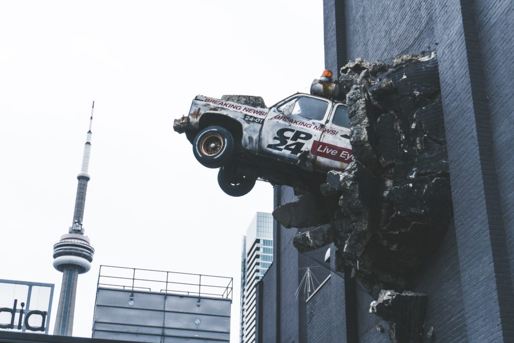 Stock image of a car sticking out of the smashed wall of a building at height